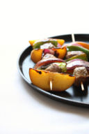 Spiedini di vitello, pesche, peperoni e cipolle
