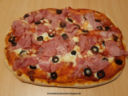 Pizza con speck cotto, mozzarella e olive nere